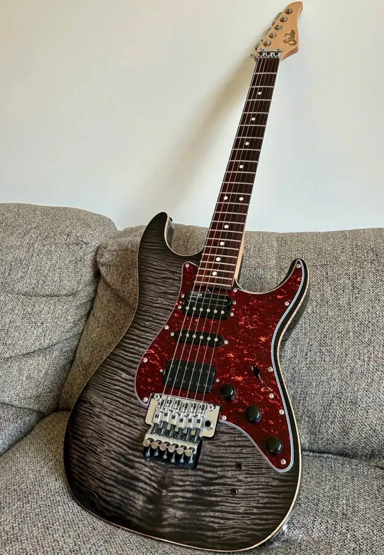 Guitare électrique table flammée posée sur un canapé